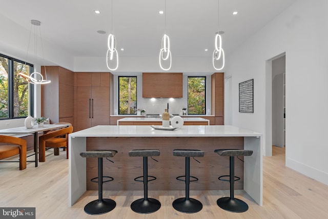 kitchen with a large island, decorative light fixtures, light wood-type flooring, and a breakfast bar area