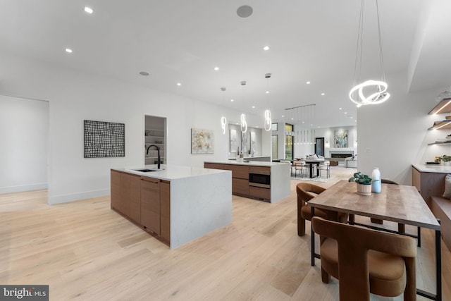 kitchen with a spacious island, light hardwood / wood-style floors, sink, and pendant lighting