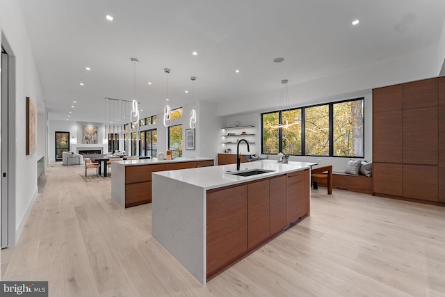 kitchen featuring a large island, sink, decorative light fixtures, and light hardwood / wood-style floors