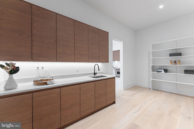 kitchen featuring sink, stainless steel stove, and light wood-type flooring