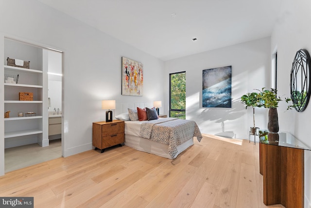 bedroom with ensuite bath and light hardwood / wood-style flooring