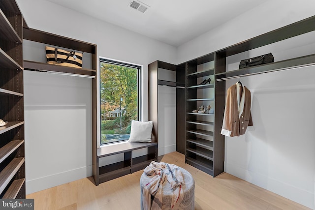 walk in closet with light hardwood / wood-style flooring