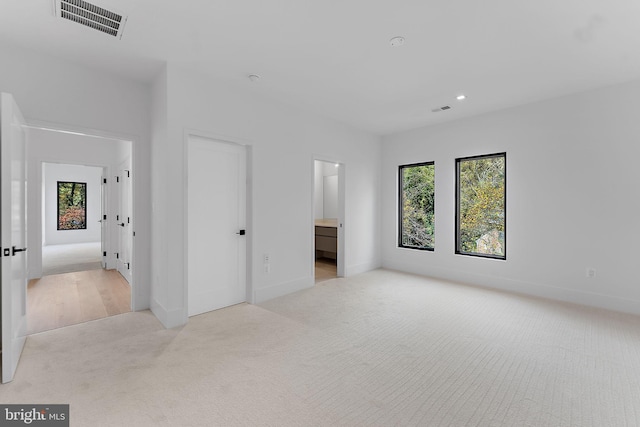 unfurnished bedroom featuring light colored carpet and ensuite bath