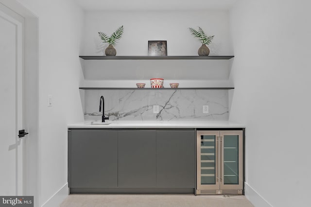 bar with wine cooler, sink, light colored carpet, and gray cabinets