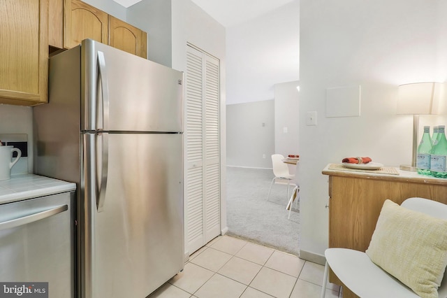 kitchen featuring light carpet, stainless steel refrigerator, light brown cabinets, and tile counters