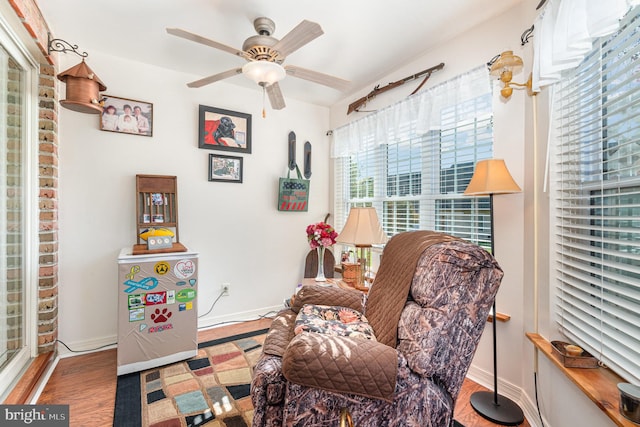 living area with wood-type flooring and ceiling fan