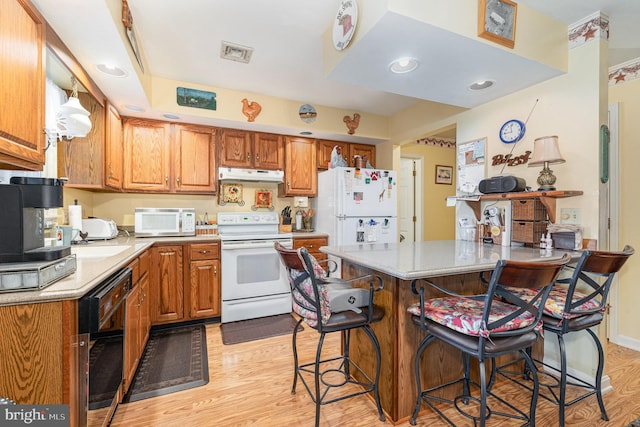 kitchen featuring light hardwood / wood-style flooring, a kitchen bar, and white appliances