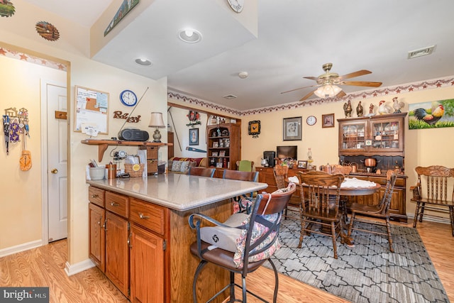 kitchen with ceiling fan, light wood-type flooring, and a kitchen breakfast bar