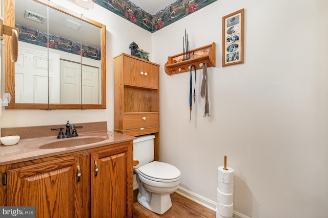 bathroom with vanity, toilet, and hardwood / wood-style floors