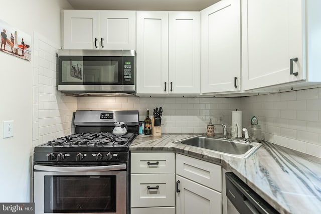 kitchen featuring white cabinetry, stainless steel appliances, sink, and backsplash