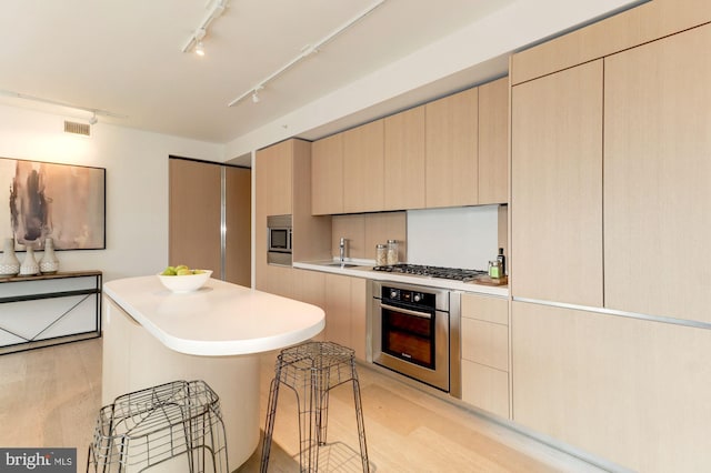 kitchen featuring stainless steel appliances, light wood-type flooring, light brown cabinetry, sink, and rail lighting