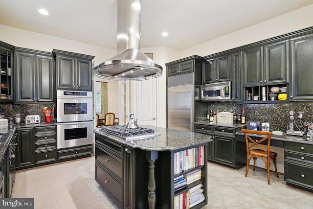 kitchen featuring backsplash, dark stone counters, appliances with stainless steel finishes, a kitchen island, and island exhaust hood