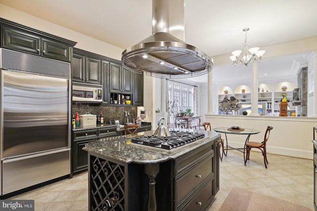 kitchen featuring dark stone counters, decorative backsplash, appliances with stainless steel finishes, a kitchen island, and island exhaust hood