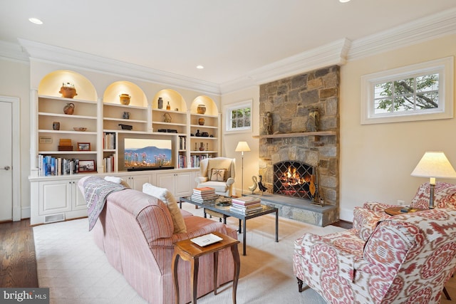 living room featuring a fireplace, built in shelves, plenty of natural light, and ornamental molding