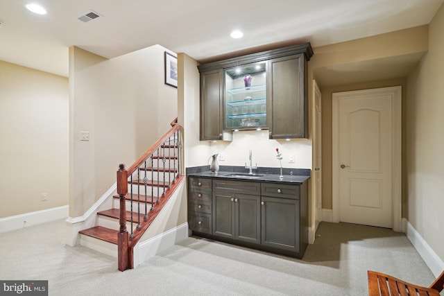 bar with sink, light colored carpet, and dark brown cabinets