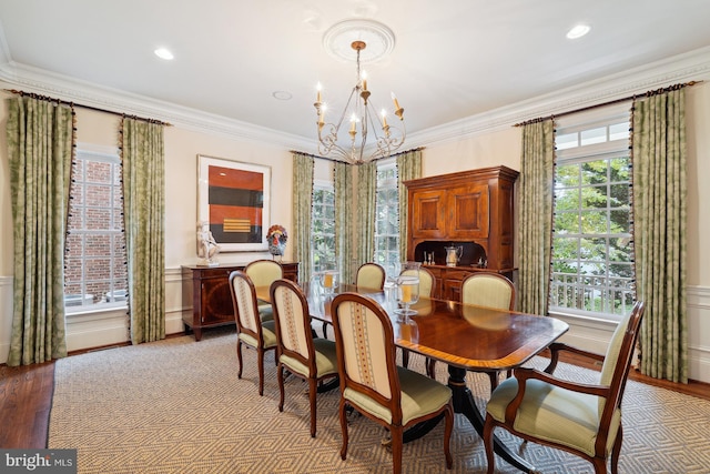 dining room with light hardwood / wood-style flooring, crown molding, and an inviting chandelier