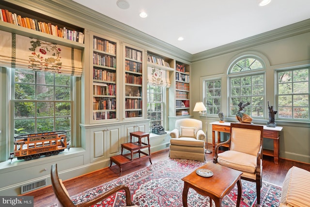 living area with hardwood / wood-style flooring, built in shelves, and ornamental molding