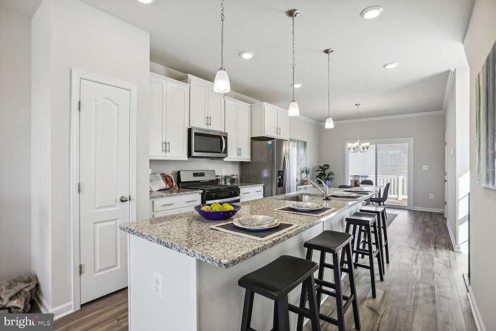 kitchen with dark hardwood / wood-style floors, a kitchen breakfast bar, an island with sink, stainless steel appliances, and white cabinetry