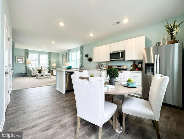 dining area with dark wood-type flooring, sink, and baseboard heating