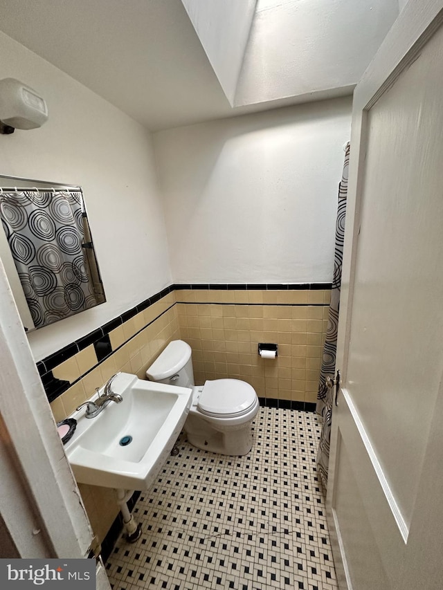 bathroom featuring toilet, sink, and tile walls