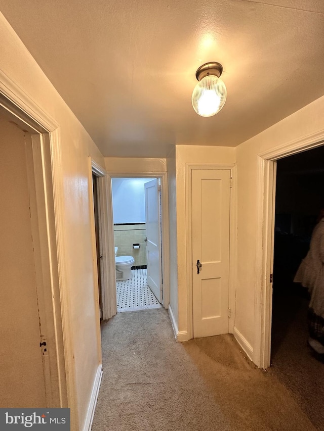 hall featuring a textured ceiling and light colored carpet