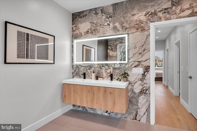 bathroom with wood-type flooring, vanity, and tile walls