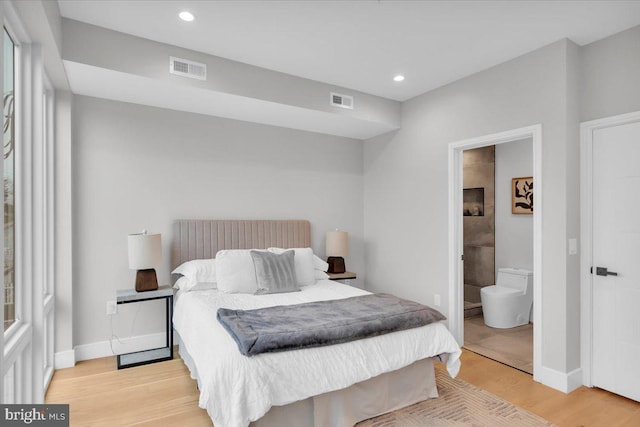 bedroom featuring connected bathroom and light hardwood / wood-style floors