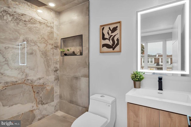 bathroom with tiled shower, vanity, and toilet