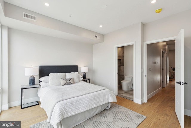 bedroom featuring ensuite bathroom and light hardwood / wood-style flooring