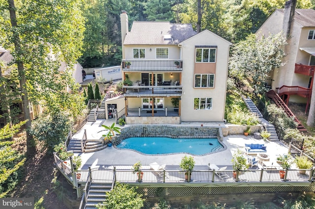 back of property featuring a fenced in pool, a patio area, and a balcony