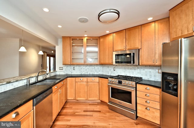 kitchen with sink, hanging light fixtures, stainless steel appliances, backsplash, and kitchen peninsula