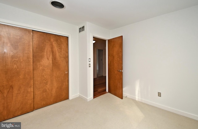 unfurnished bedroom featuring light colored carpet and a closet