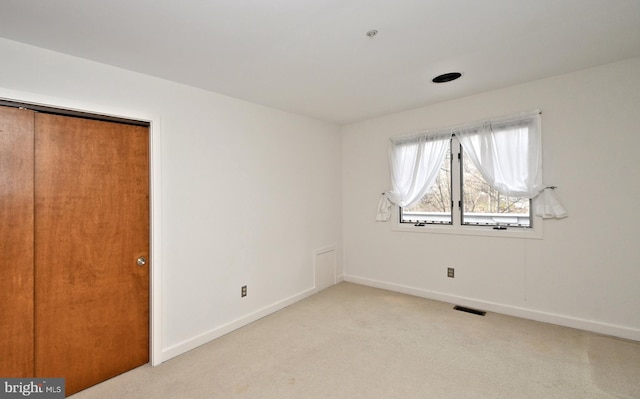 unfurnished bedroom featuring light colored carpet and a closet