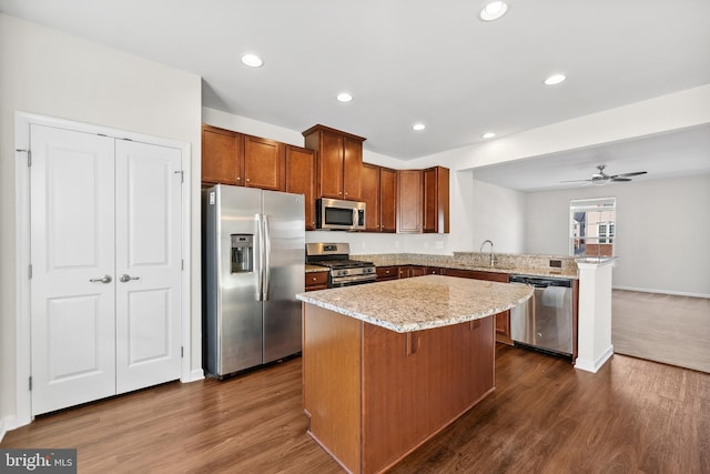 kitchen with dark hardwood / wood-style flooring, a kitchen island, kitchen peninsula, and appliances with stainless steel finishes