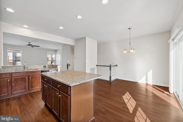 kitchen with dark wood-type flooring, a kitchen island, hanging light fixtures, and sink