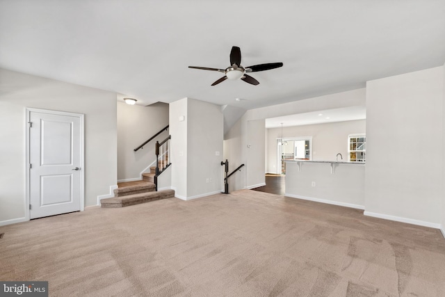 unfurnished living room with carpet and ceiling fan with notable chandelier