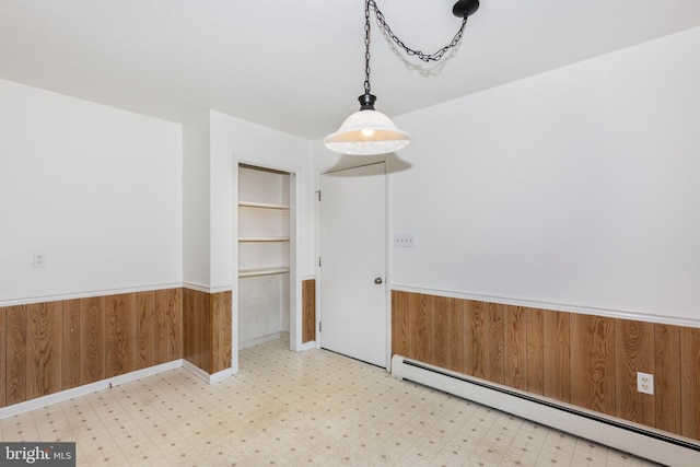 unfurnished dining area featuring built in shelves, wood walls, and baseboard heating