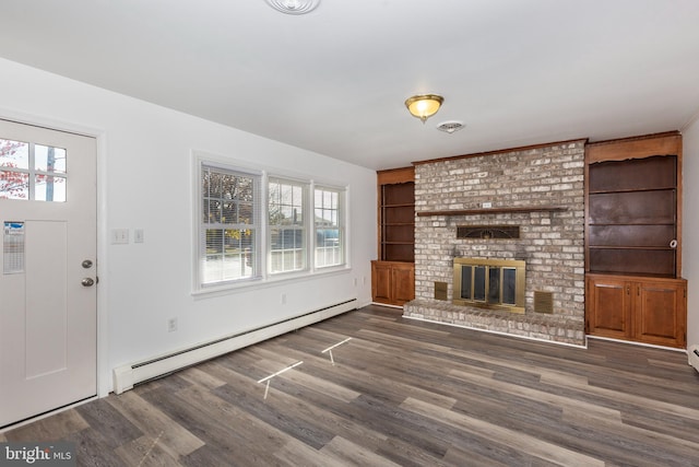 unfurnished living room with dark wood-type flooring, baseboard heating, a healthy amount of sunlight, and a brick fireplace