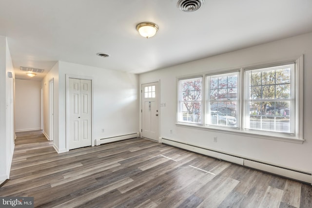 foyer with a baseboard heating unit and wood-type flooring