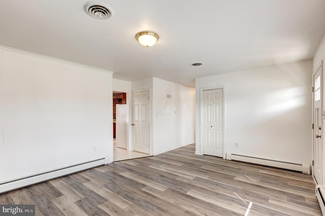 empty room featuring light hardwood / wood-style floors and a baseboard heating unit