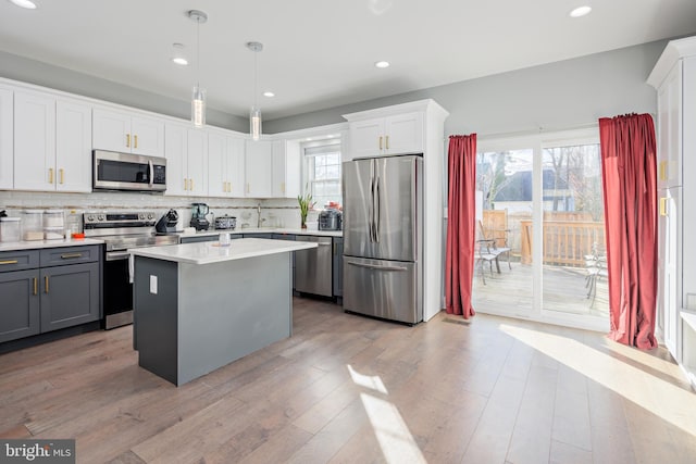 kitchen featuring gray cabinetry, tasteful backsplash, decorative light fixtures, white cabinets, and appliances with stainless steel finishes