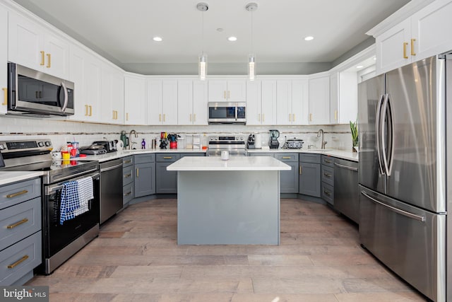 kitchen with a center island, hanging light fixtures, gray cabinets, white cabinets, and appliances with stainless steel finishes