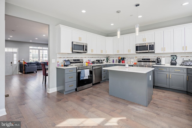 kitchen with white cabinets, appliances with stainless steel finishes, decorative light fixtures, and gray cabinetry