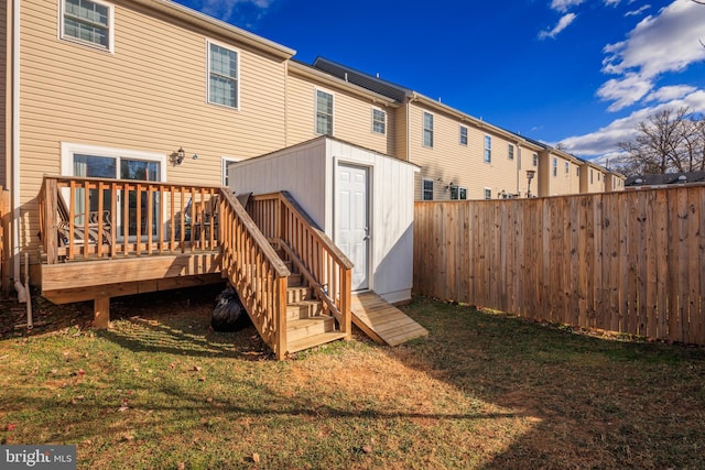 rear view of house with a storage unit, a wooden deck, and a lawn