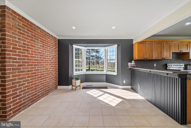 kitchen featuring tasteful backsplash, stainless steel range with electric stovetop, crown molding, brick wall, and light tile patterned floors