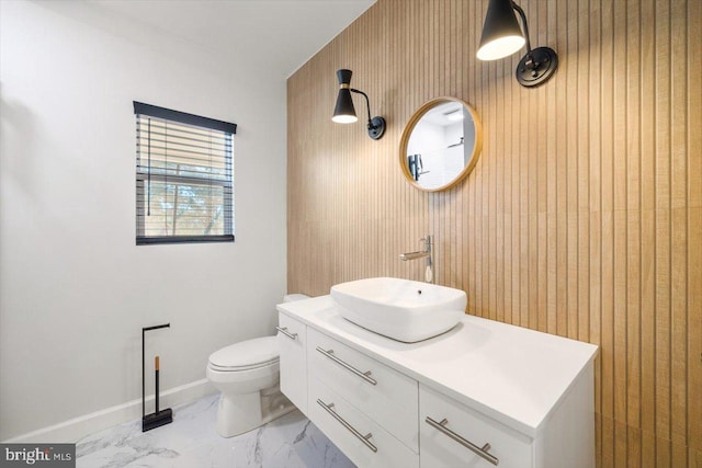 bathroom with vanity, wooden walls, and toilet