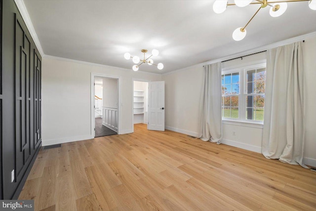 unfurnished bedroom featuring crown molding, a notable chandelier, and light wood-type flooring