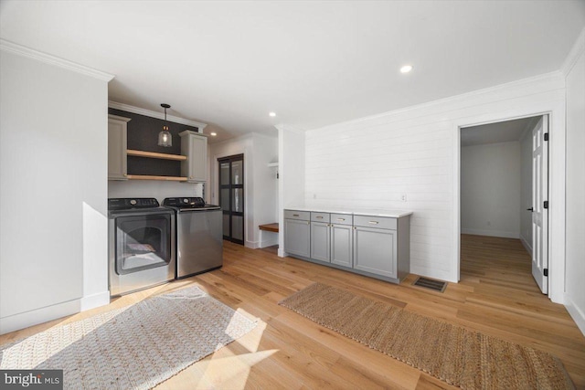 kitchen featuring ornamental molding, pendant lighting, gray cabinetry, light hardwood / wood-style floors, and washer and clothes dryer