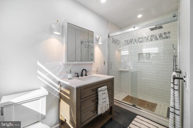 bathroom featuring a shower with door and vanity