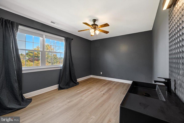 unfurnished room featuring sink, light hardwood / wood-style floors, and ceiling fan